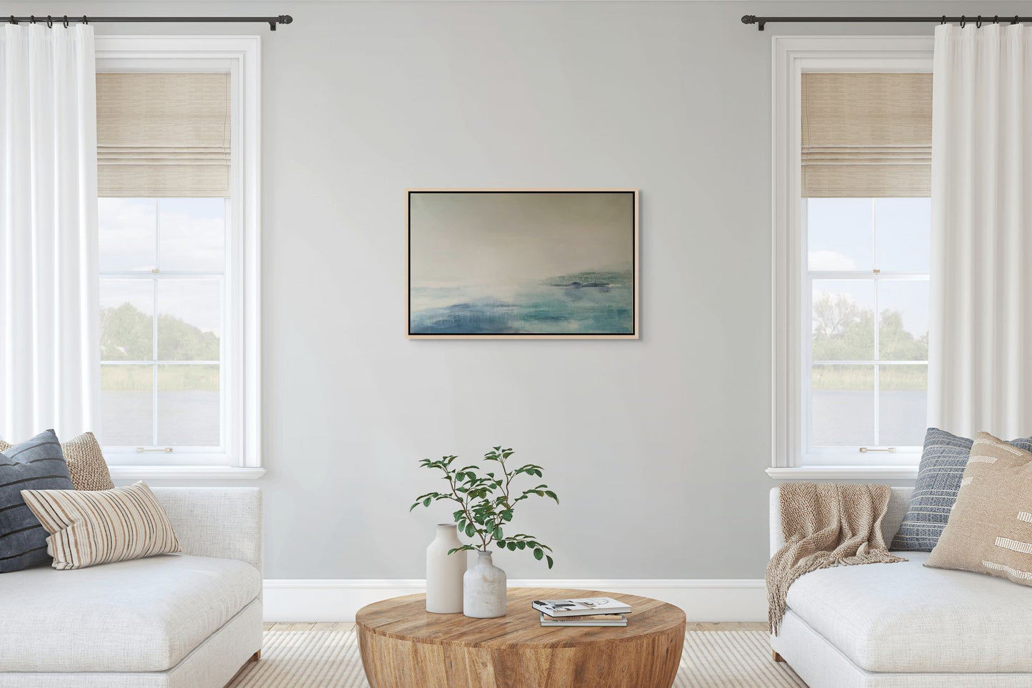 Living room with white walls, large windows, abstract blue seascape and a wooden coffee table.