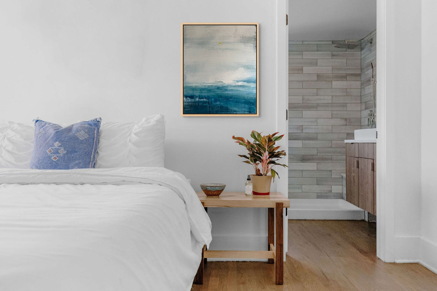 Bedroom with a bed, bedside table, and abstract seascape original painting