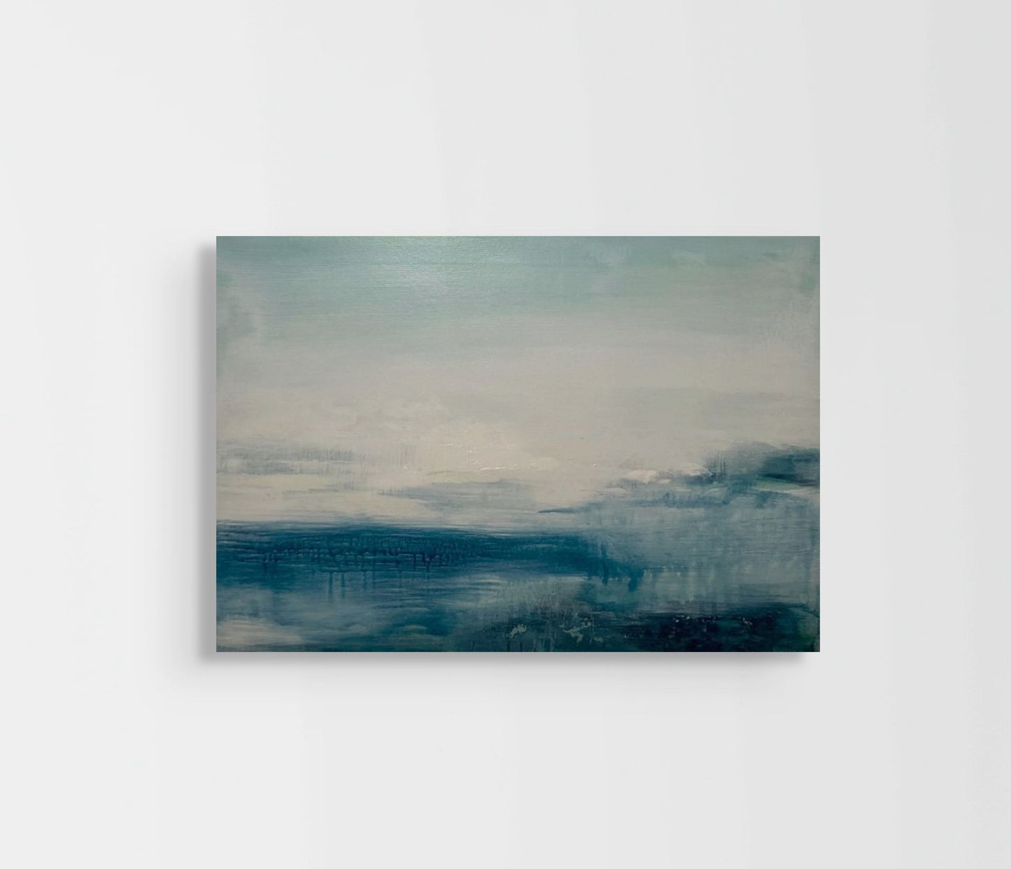 Abstract painting with blue and gray tones on a white wall
