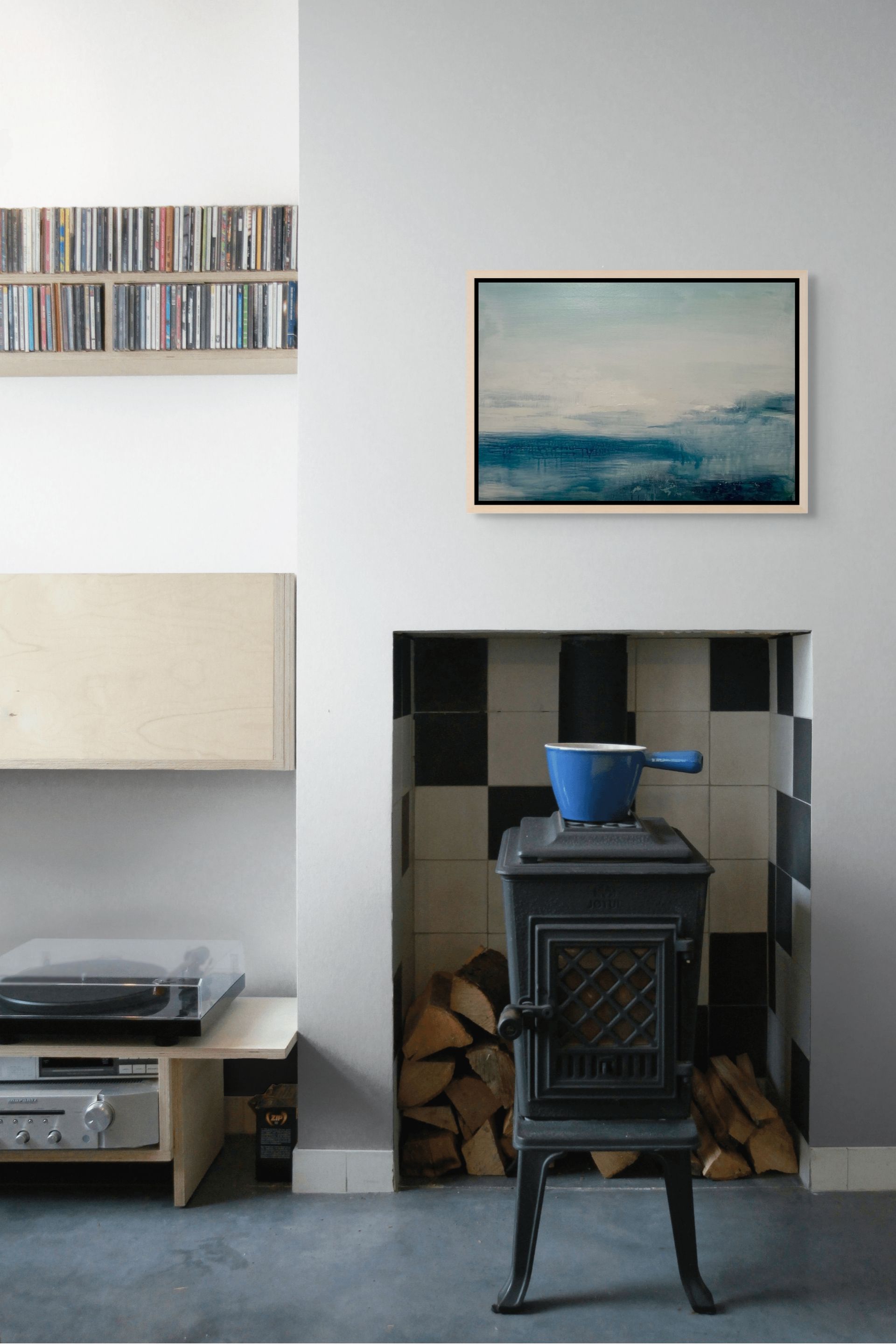 Small stove with a blue pot inside a room with a shelf, blue abstract seascape artwork, and record player.